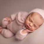 девочка недавно родилась лежит в пушистом ангоровом костюме в розовом чепчике рука на щеке спит