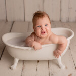 малыш до года с пухлыми щеками купается в ванне с пеной