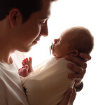 молодой папа держи на руках новорожденную дочку замотанную в пеленку