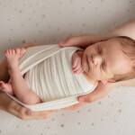 новорожденная девочка в пеленке в папиных руках на муслиновой пеленке со звездочками до луны и обратно