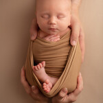 новорожденный в пеленке лежит в руках родителей