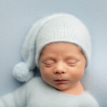 новорожденный мальчик портрет на голубом фоне в шапке гнома спит