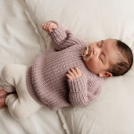 новорожденный ребенок девочка спит в вязанном свитере с соской бибс