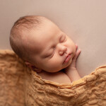 портрет новорожденного ребенка укрытого ажурной марлбю желтой горчичного цвета