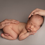 руки родителей лежат на новорожденном сыне